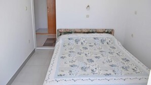A small, narrow room with a single bed, a door, and a tiled floor. - House Jasna (Igrane)