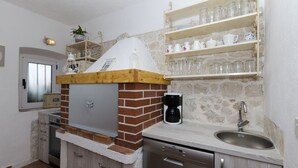 A kitchen with a brick oven, a coffee maker, and shelves with glassware. - House Jasna (Igrane)