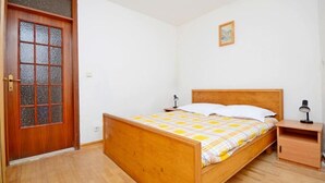 Une chambre à coucher avec un lit en bois, une table de chevet, une lampe et une porte dotée d’un panneau en verre.