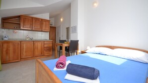 A bedroom with a bed, a desk, and a kitchenette. - Apartments Mara (Vodice)