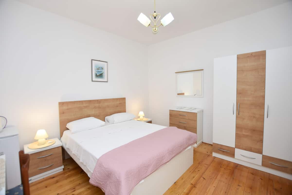 Un dormitorio con cama, mesitas de noche, armario y una lámpara en el techo.