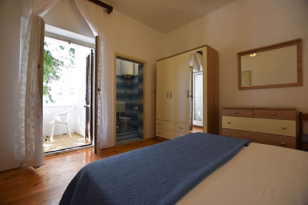 Un dormitorio con cama, armario, espejo y puerta que da a un balcón.