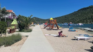 Egy játszótérrel, sétánnyal és csónakokkal felszerelt strand.