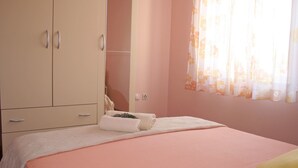 A bedroom with a bed, a wardrobe, and a window with curtains. - Apartment Anton (Slatine)