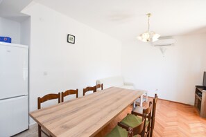 Una cocina compacta con una mesa de comedor de madera, sillas, un refrigerador blanco y un mueble pequeño blanco.