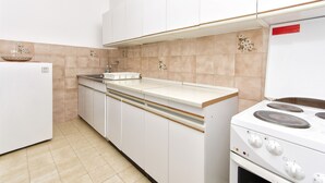 A kitchen with white cabinets, a stove, and a sink. - Apartment Niko (Vodice)