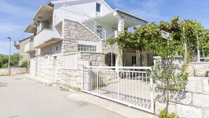 A modern two-story house with a stone facade, a balcony, and a gated entrance. - Apartment Niko (Vodice)