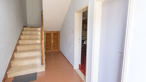 A hallway with a marble staircase, a door leading to a room with a red carpet, and a wooden door in the background. - Apartment Smiljan (Primosten)