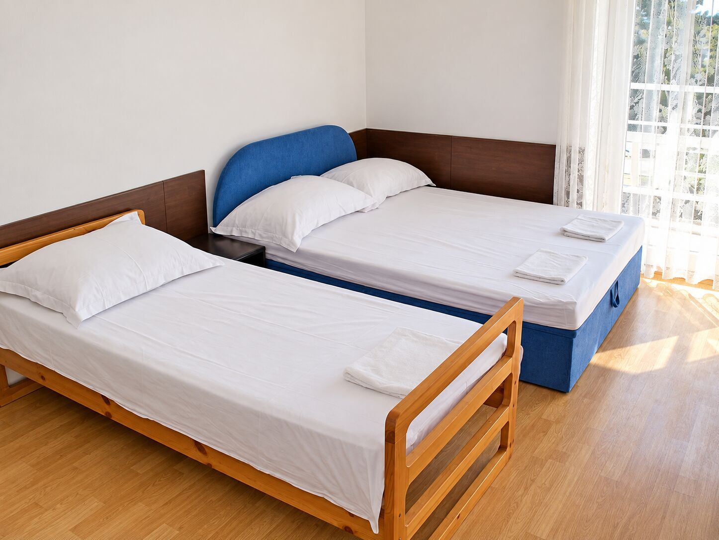 Una habitación con dos camas individuales, cabeceros de madera, ropa de cama blanca y una ventana con cortinas.