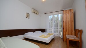 Een hotelkamer met twee bedden, een houten stoel, een raam met gordijnen en een schilderij aan de muur.