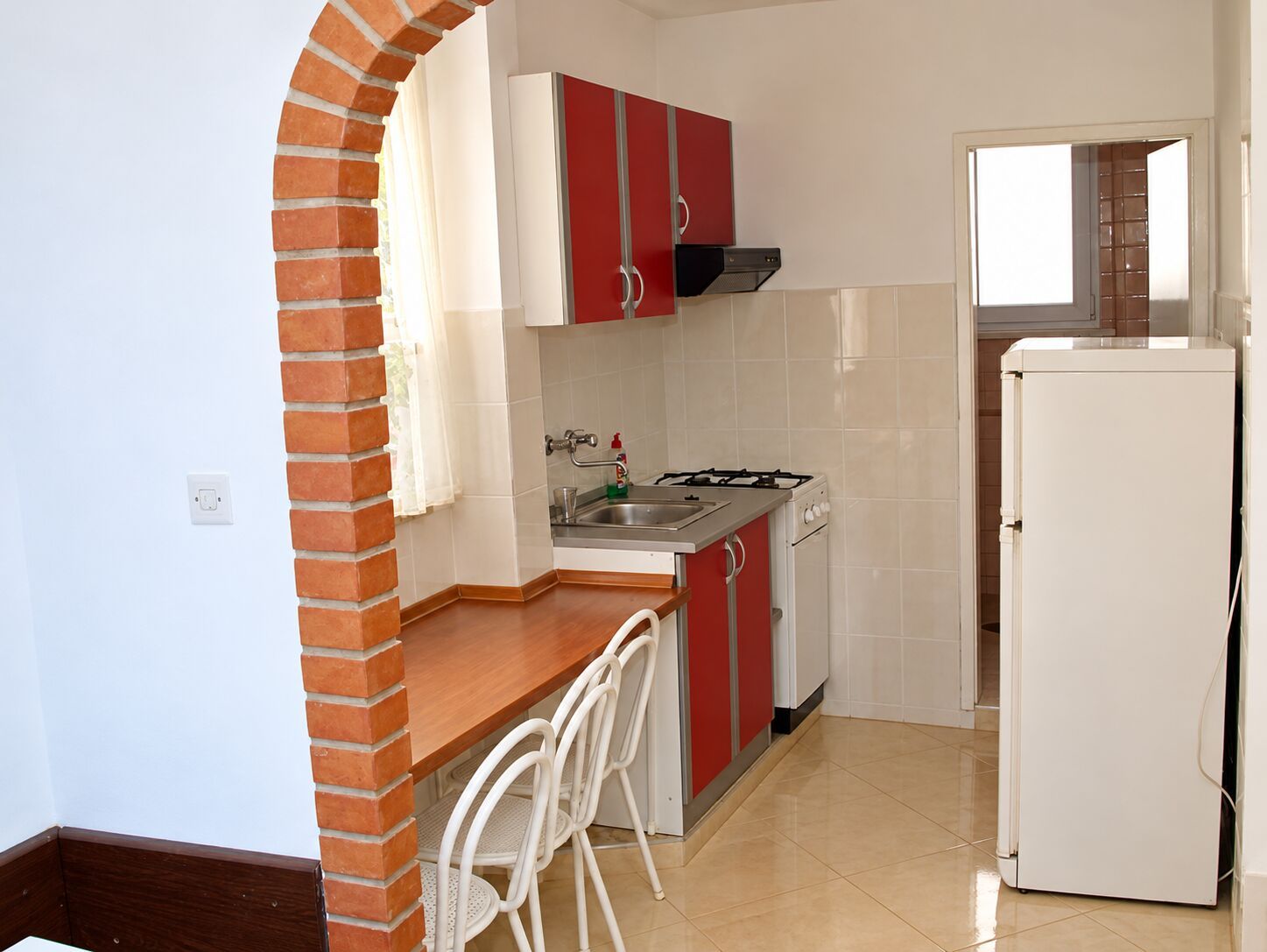 A compact kitchen with a gas stove, sink, and white refrigerator.