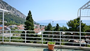 Een balkon met uitzicht op een kustplaatsje, een berg en een heldere lucht.