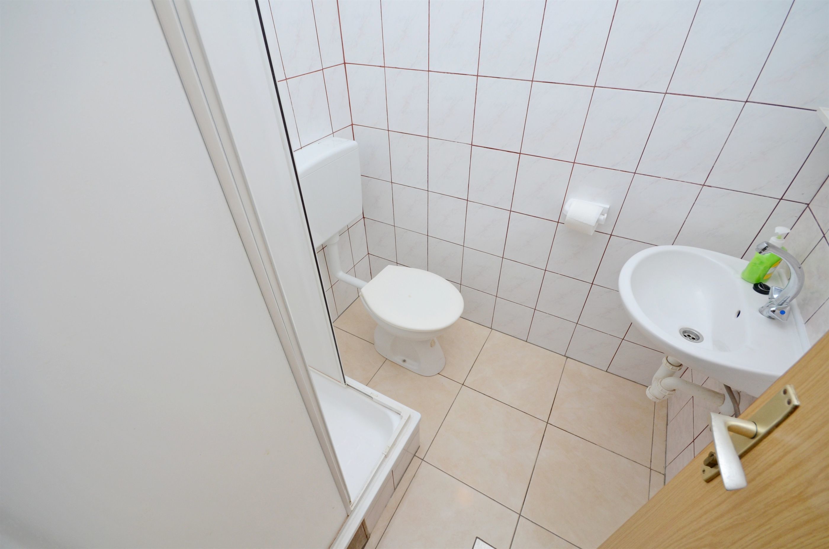 A small, clean bathroom with a toilet, sink, and shower area.