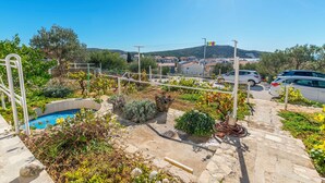 A residential area with a swimming pool, stone pathway, and parked cars. - Apartments and Room Milka-jere (Primosten)