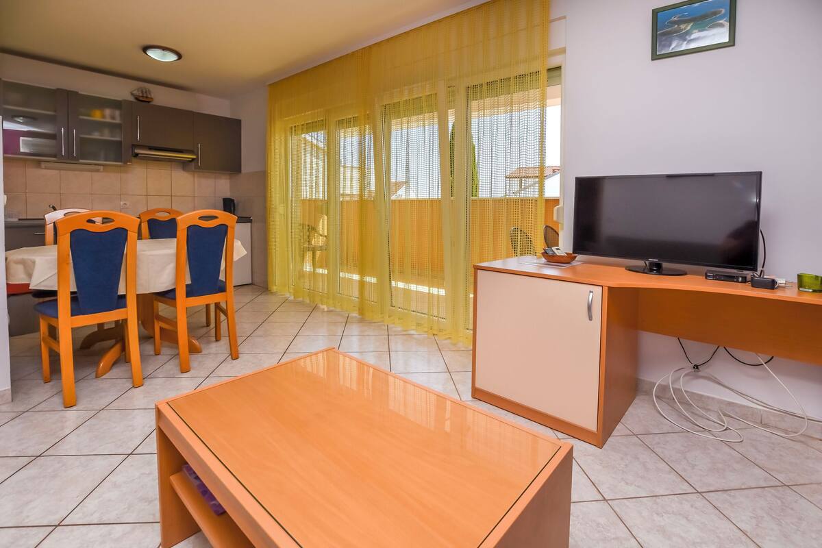 A compact living space with a dining area, a TV, and a kitchen.