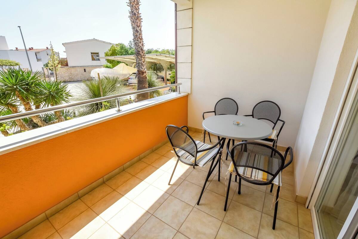 A balcony with a table and chairs, a railing, and a view of the neighborhood.