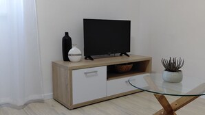 Une chambre moderne avec un meuble en bois, une table en verre et un téléviseur.