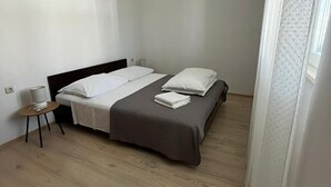 Une petite pièce propre, avec un lit, une petite table et une fenêtre.