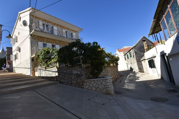A stone building with a balcony, a staircase leading to the entrance, and a clear blue sky.