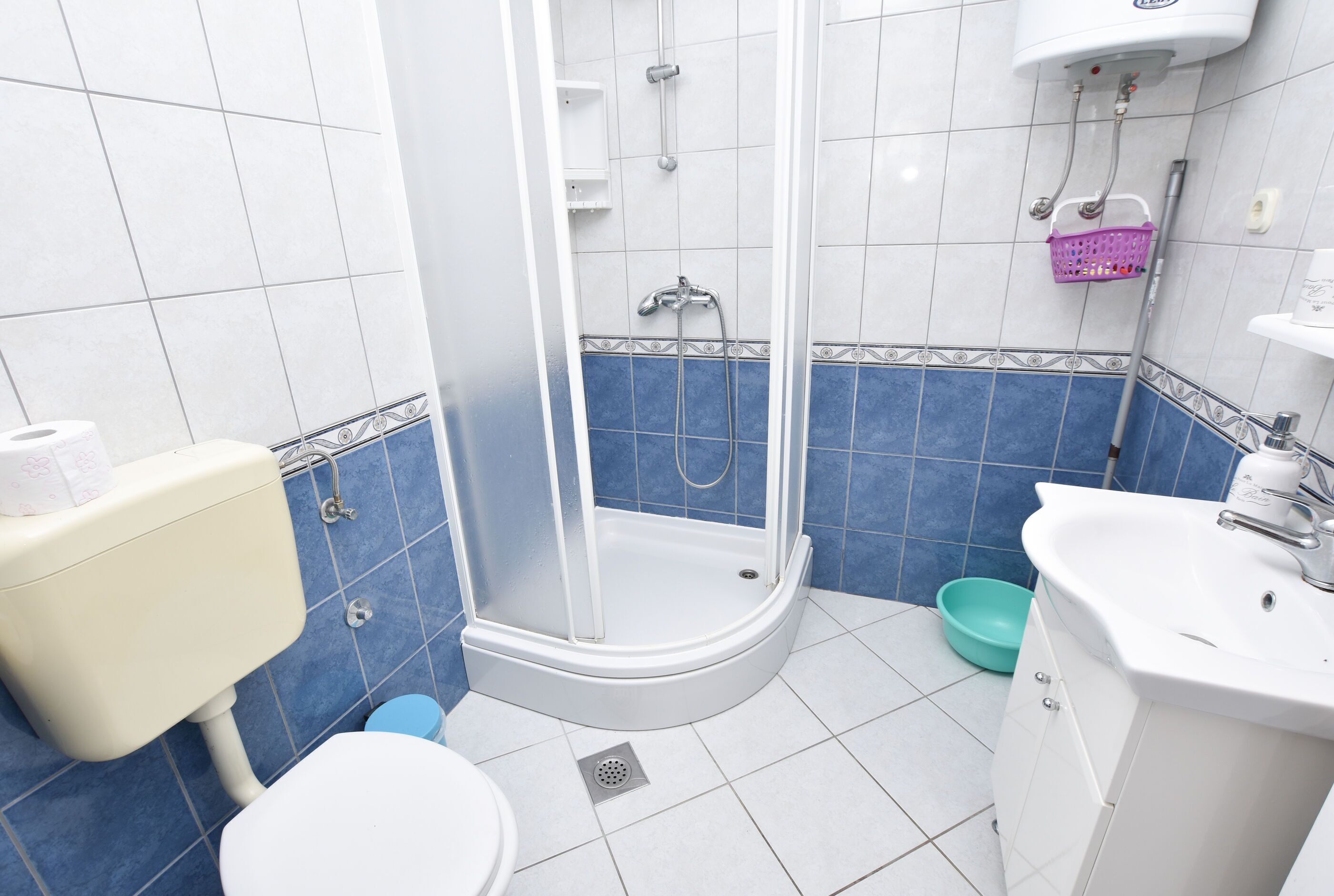 Un bagno con il water, doccia, lavandino e una parete piastrellata di blu.
