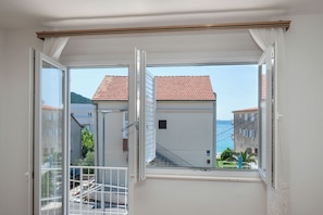 A balcony with a view of a coastal town, a white railing, and a clear sky. - Apartment Marin (Primosten)