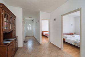 A hallway leading to a bedroom with a bed, a wooden cabinet, and a door. - Apartment Marin (Primosten)