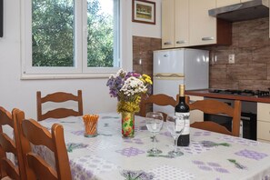 A dining table with chairs, a vase with flowers, wine glasses, and a bottle of wine. - Apartment Marin (Primosten)