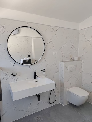 A modern bathroom with a white sink, black faucet, and a round mirror. - Apartments Beba55 m (Primosten)