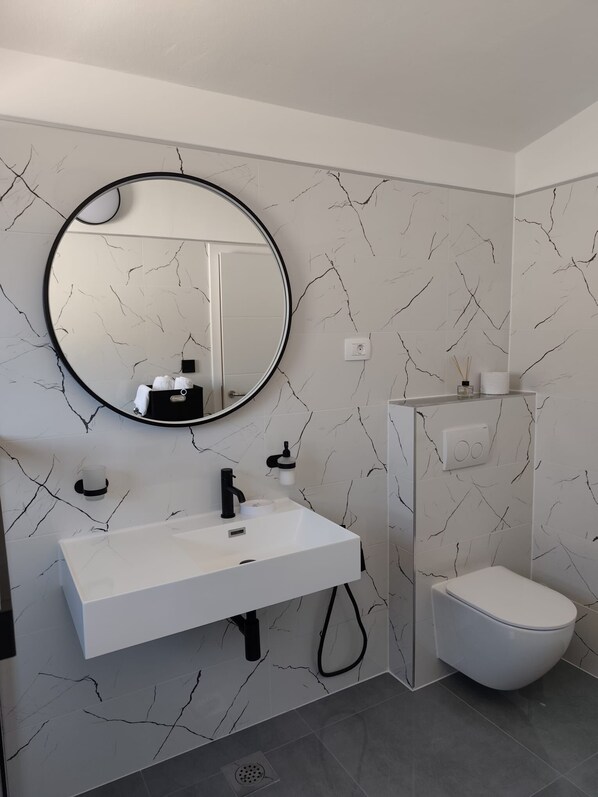 Une salle de bain moderne avec un meuble-lavabo blanc, un robinet noir et un miroir rond.
