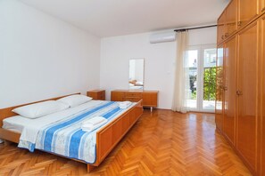 A bedroom with a wooden bed, a bedside table, a dresser, a mirror, and a sliding glass door leading to a balcony. - Apartment Davorka (Primosten)