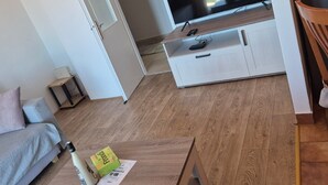 A modern living room with a flat-screen TV, a wooden coffee table, and a grey sofa. - Apartment Bore (Primosten)