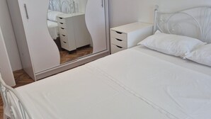 A bedroom with a bed, a white wardrobe with a mirror, and a bedside table. - Apartment Bore (Primosten)