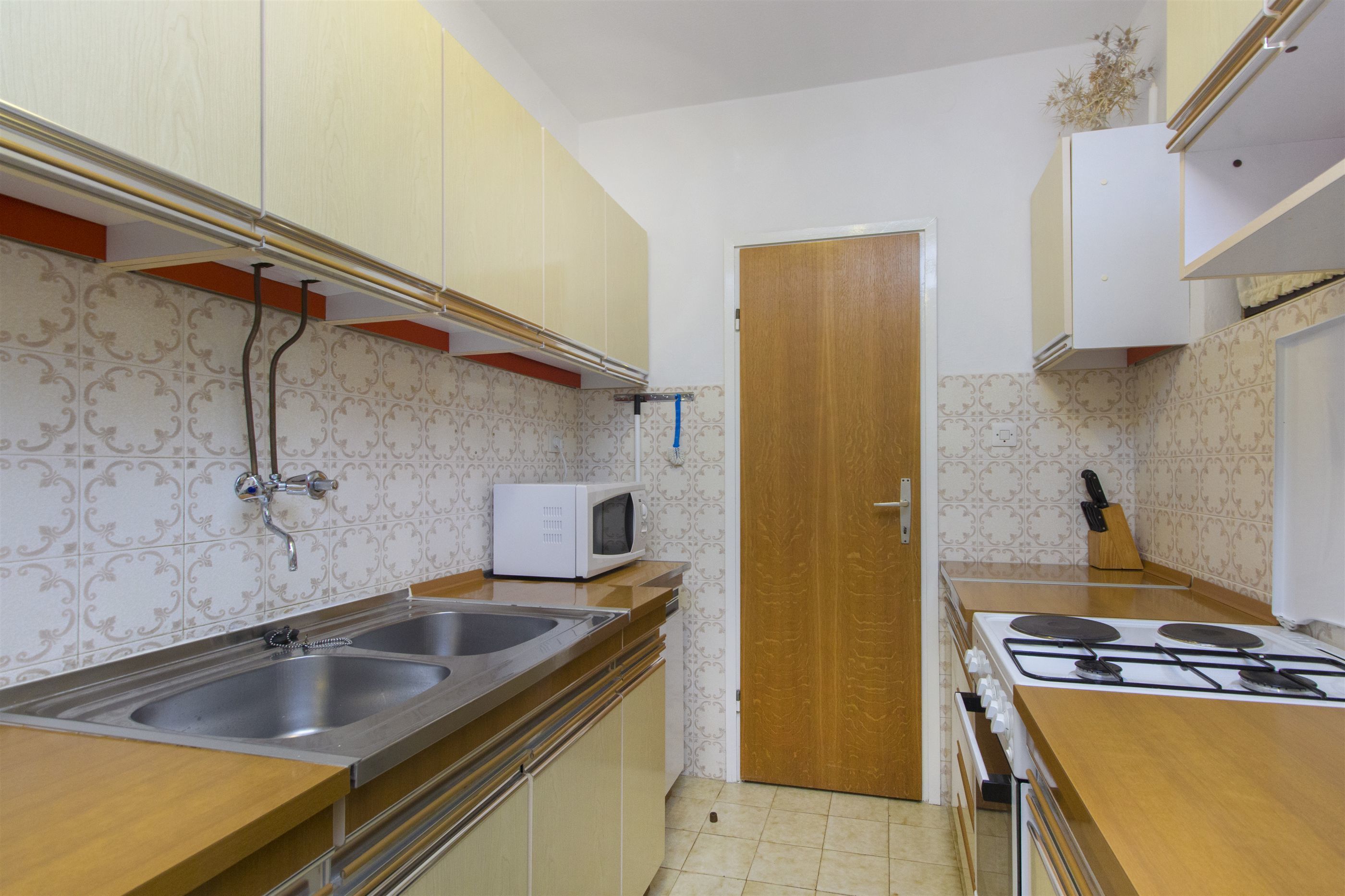 A compact kitchen with a sink, microwave, stove, and wooden cabinets.