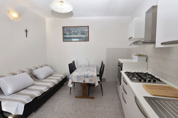 A compact kitchen with a dining table, a sofa, and a stove.