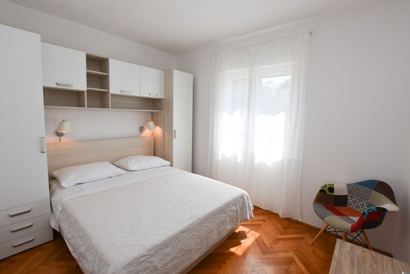 A bedroom with a bed, a wardrobe, a desk, and a chair. - Apartments Guzela (Primosten)