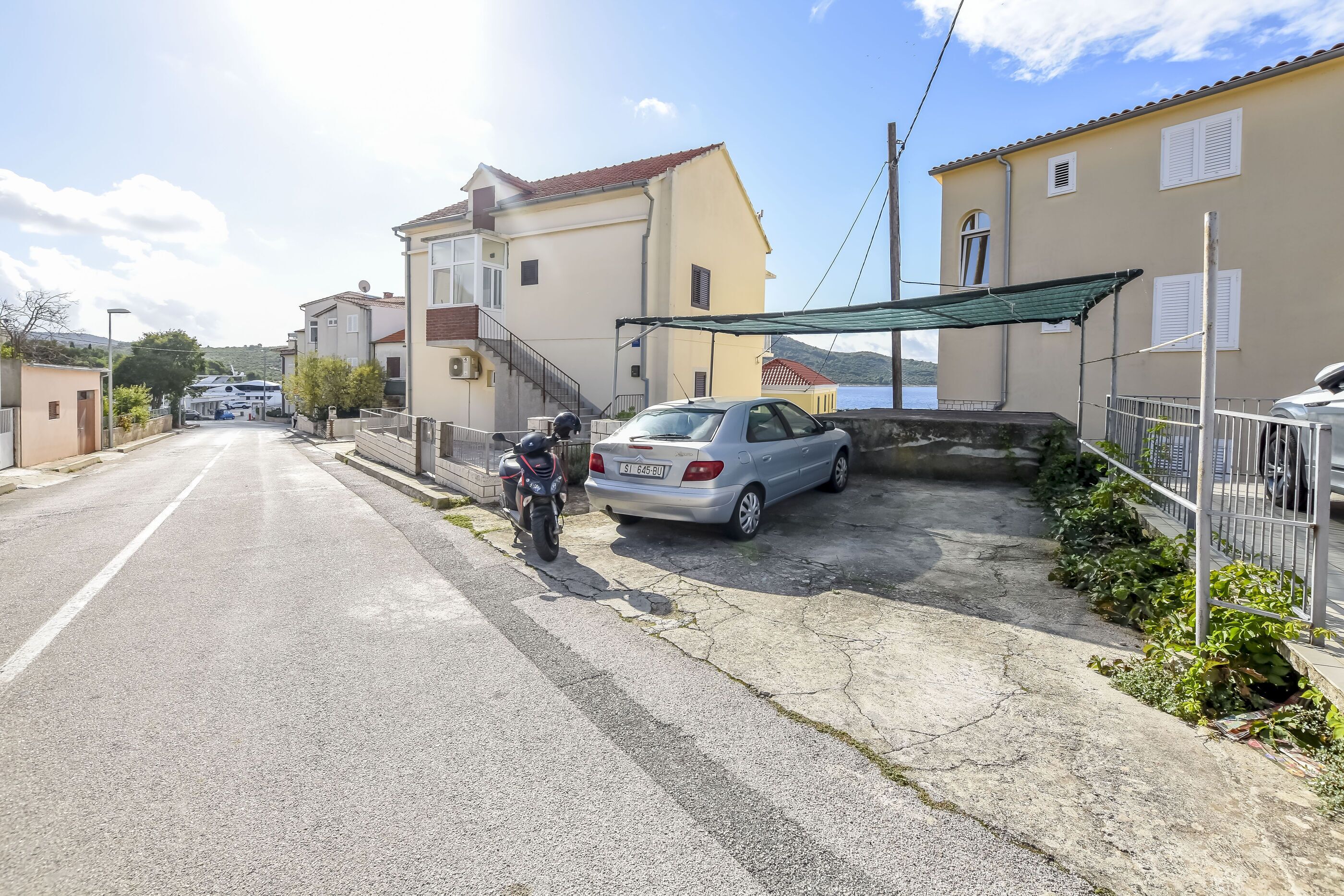 Una calle residencial con casas, un automóvil estacionado y una motocicleta.
