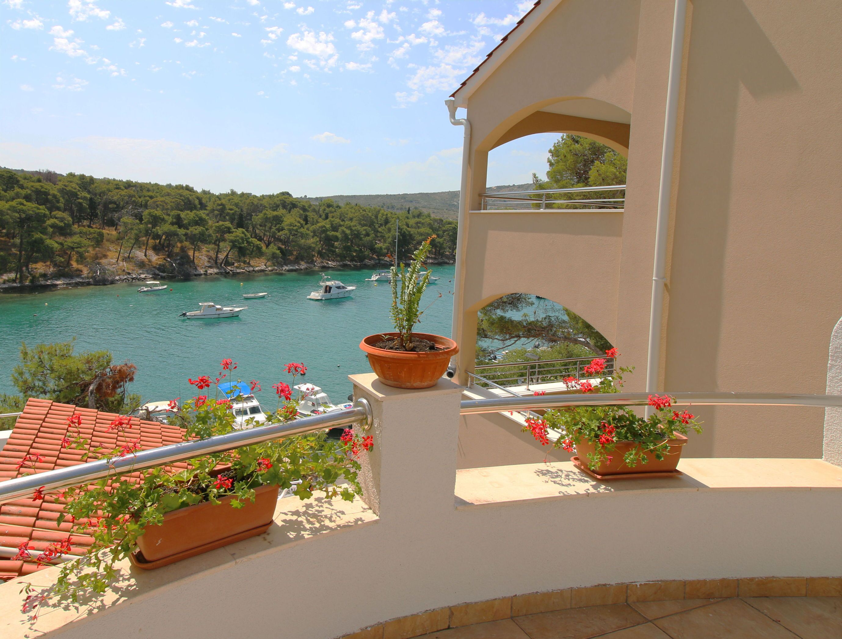 Un balcon agrémenté de plantes en pot, offrant une vue sur des bateaux naviguant sur une mer calme.