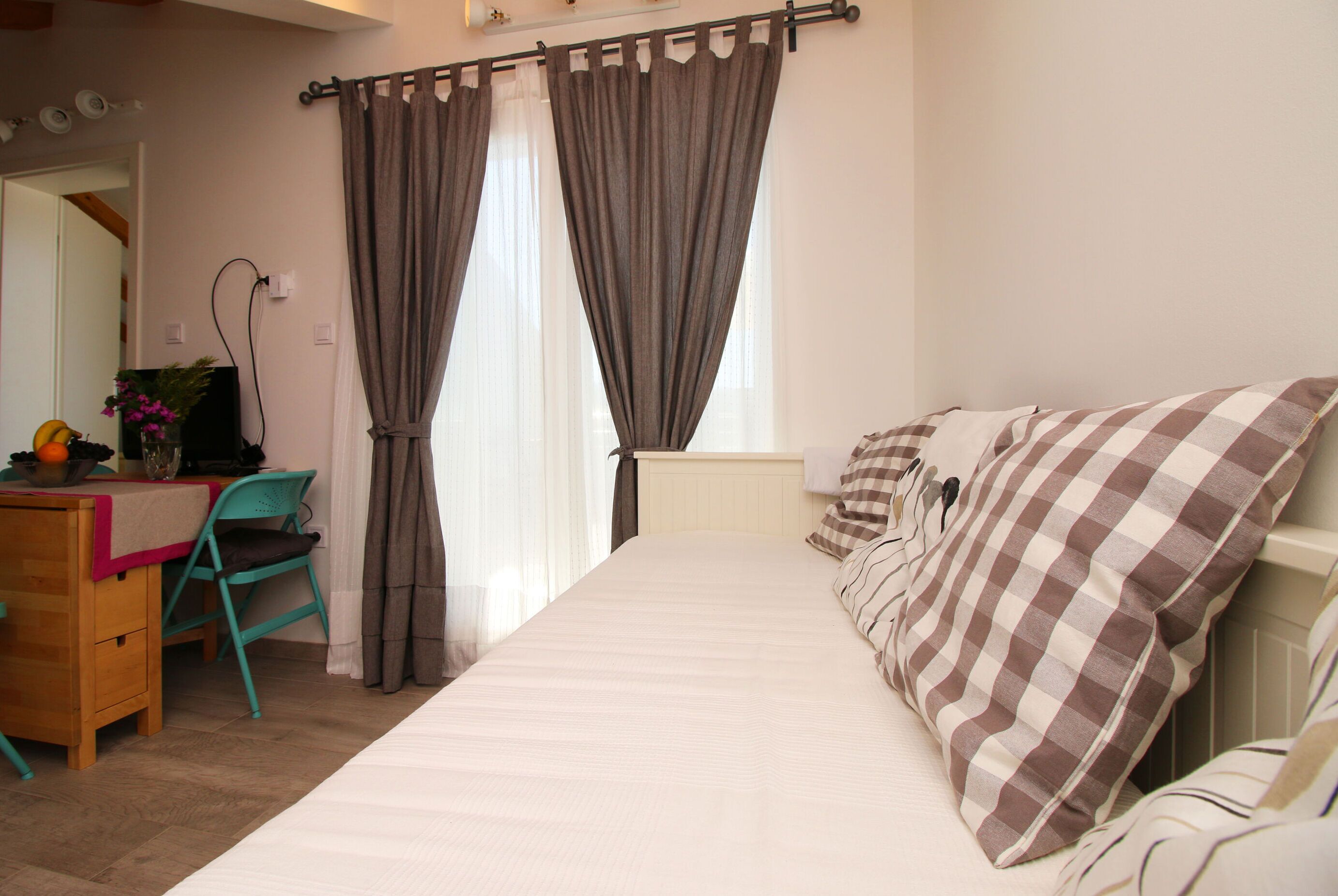 A bedroom with a bed, a desk with a chair, and a window with curtains.