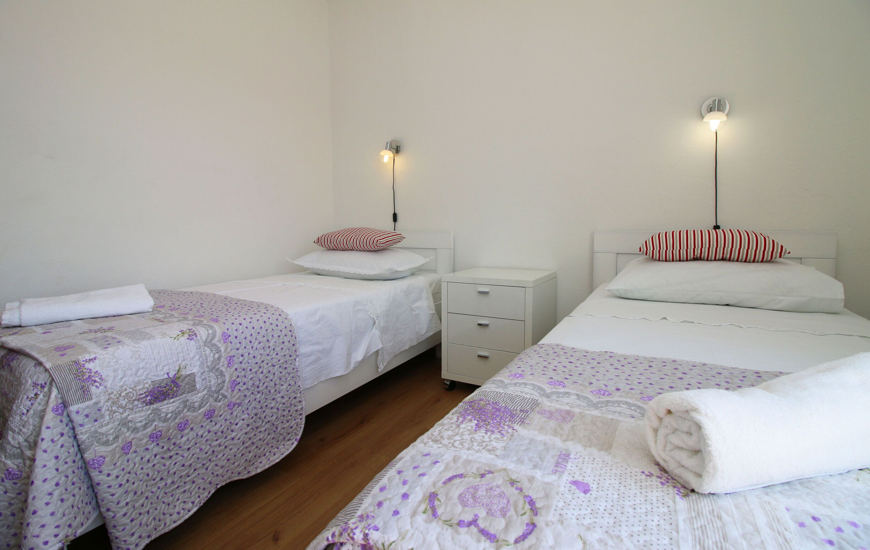 A bedroom with two beds, each with a pillow and a bedside table.