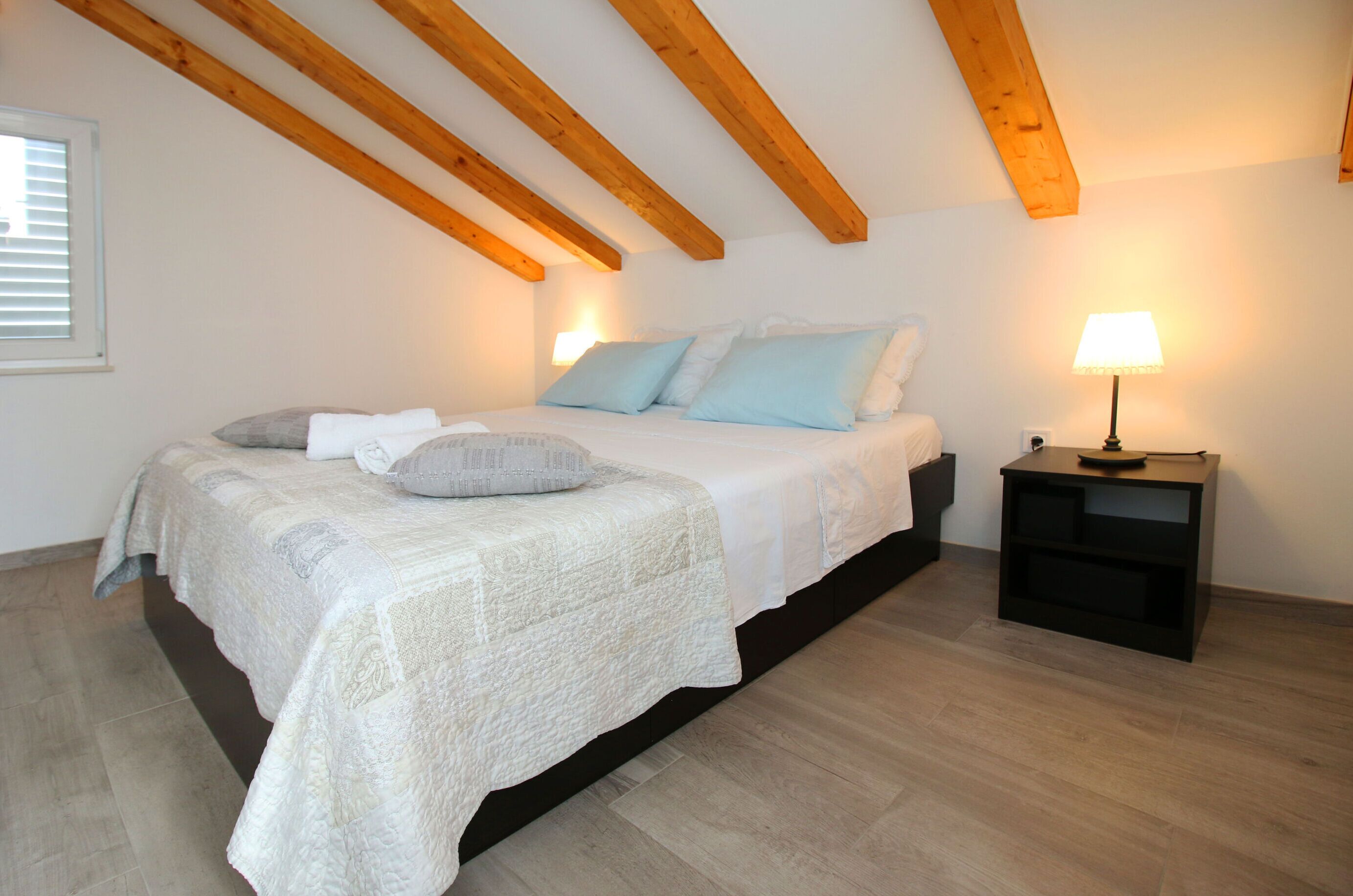 A bedroom with a bed, pillows, a nightstand, and a lamp.