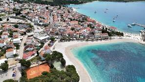 An aerial view of a coastal town with a beach, clear blue waters, and boats. - Apartments Brico (Primosten)