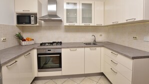 Una cocina moderna con armarios blancos, un microondas, una estufa a gas y un horno.