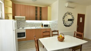 Una cocina con armarios de madera, una encimera blanca, un microondas, un horno y una mesa de comedor con sillas.