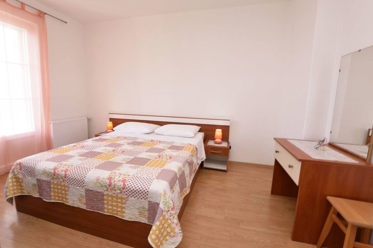 Une chambre à coucher avec un lit en bois, une table de chevet avec une lampe, une commode en bois et un miroir.