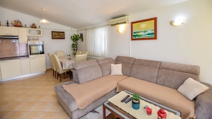 Una sala de estar con un sofá, una mesa de comedor con sillas y una zona de cocina con armarios y electrodomésticos.
