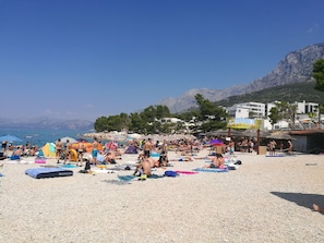 Una playa concurrida con sombrillas y gente tomando el sol.