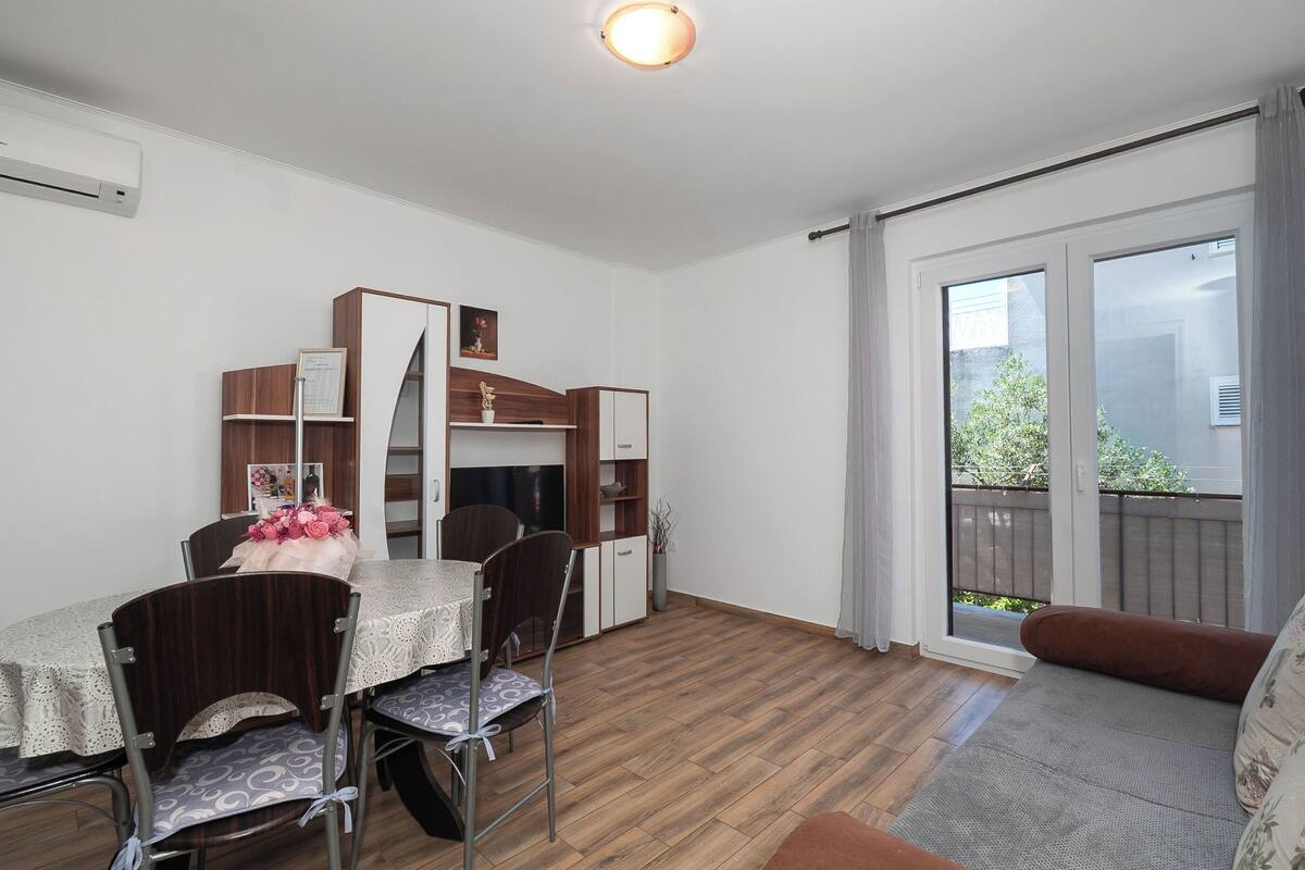 Un coin repas avec une table dressée pour quatre personnes, un canapé et une porte-fenêtre coulissante donnant sur un balcon.