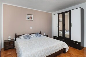 A bedroom with a bed, nightstands, a wardrobe, and a wall-mounted picture. - Apartments Katica (Primosten)