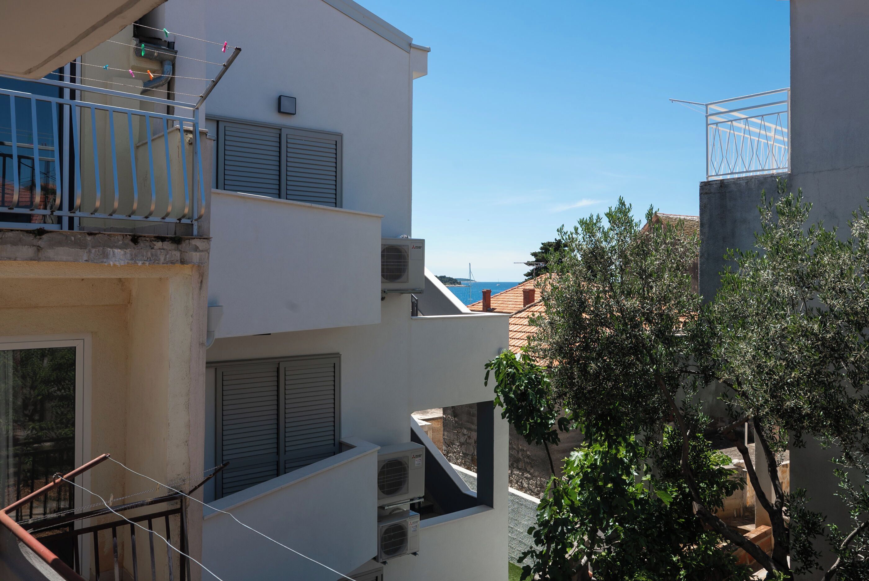 A multi-story building with balconies, air conditioning units, and a view of the sea.