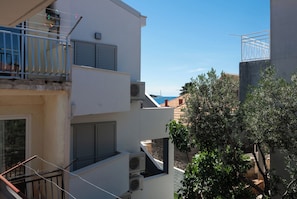 A multi-story building with balconies, air conditioning units, and a view of the sea. - Apartments Katica (Primosten)